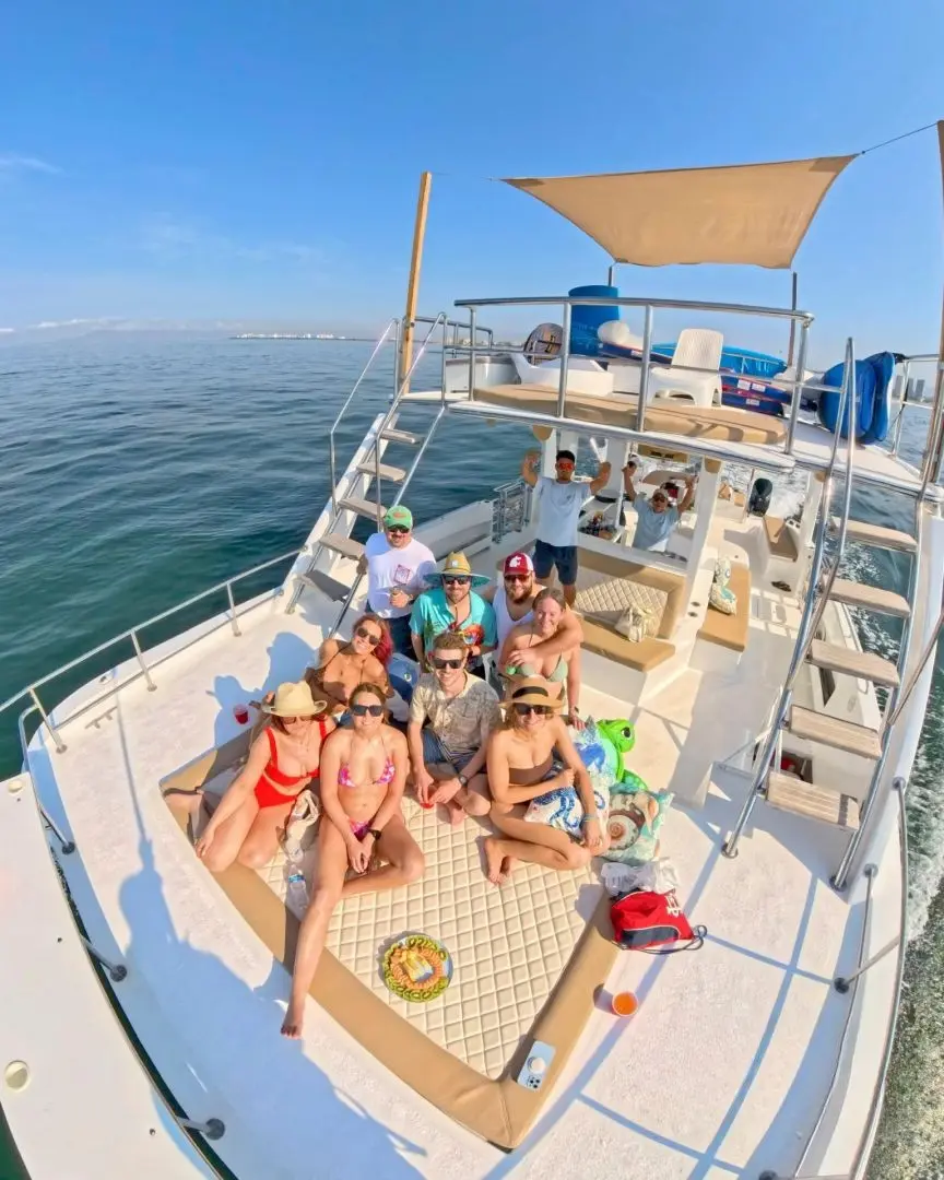 A group of guests pose on the front deck of the catamaran beneath its shaded upper level
