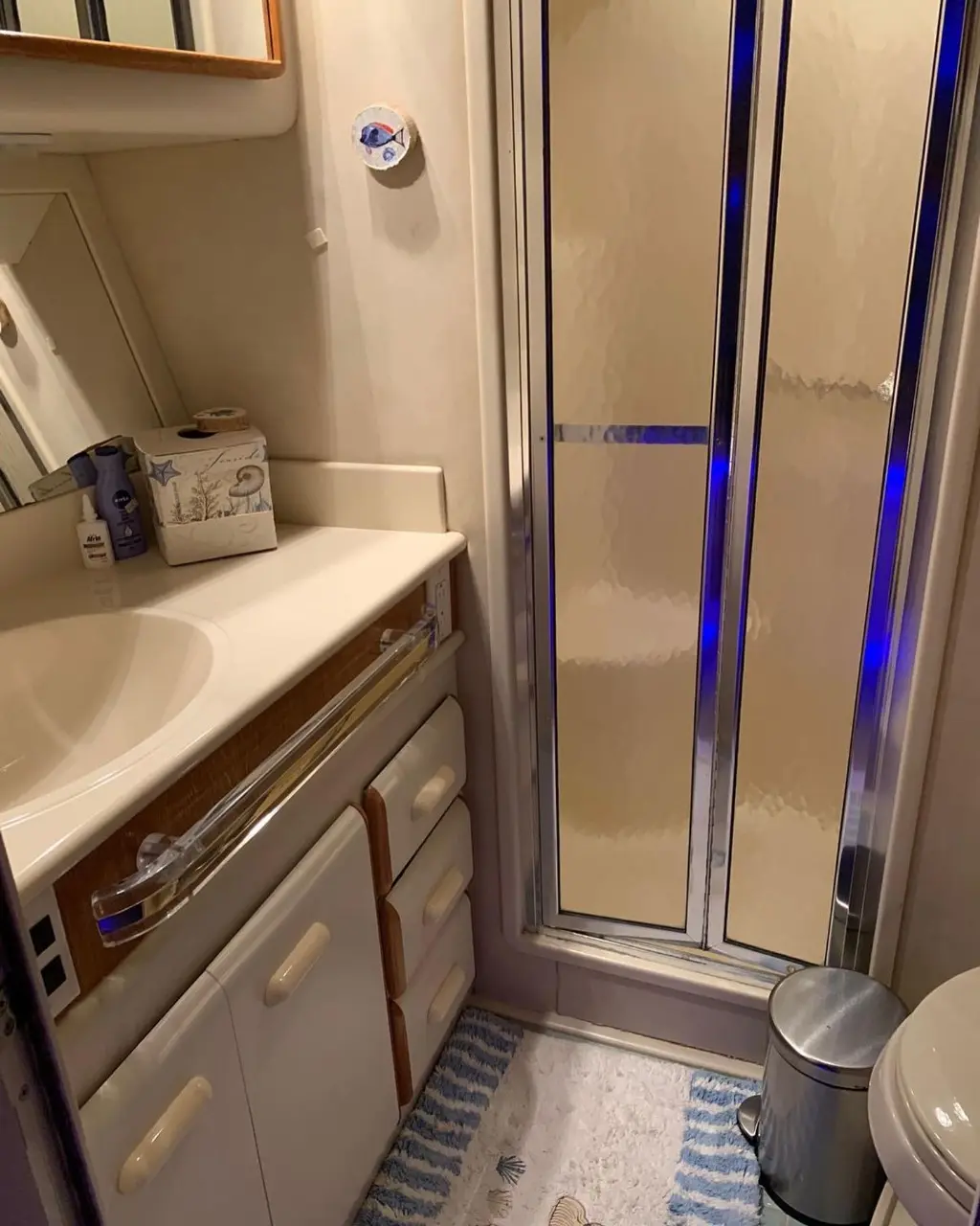 Yacht bathroom with a vanity sink, glass-door shower and blue accent lighting