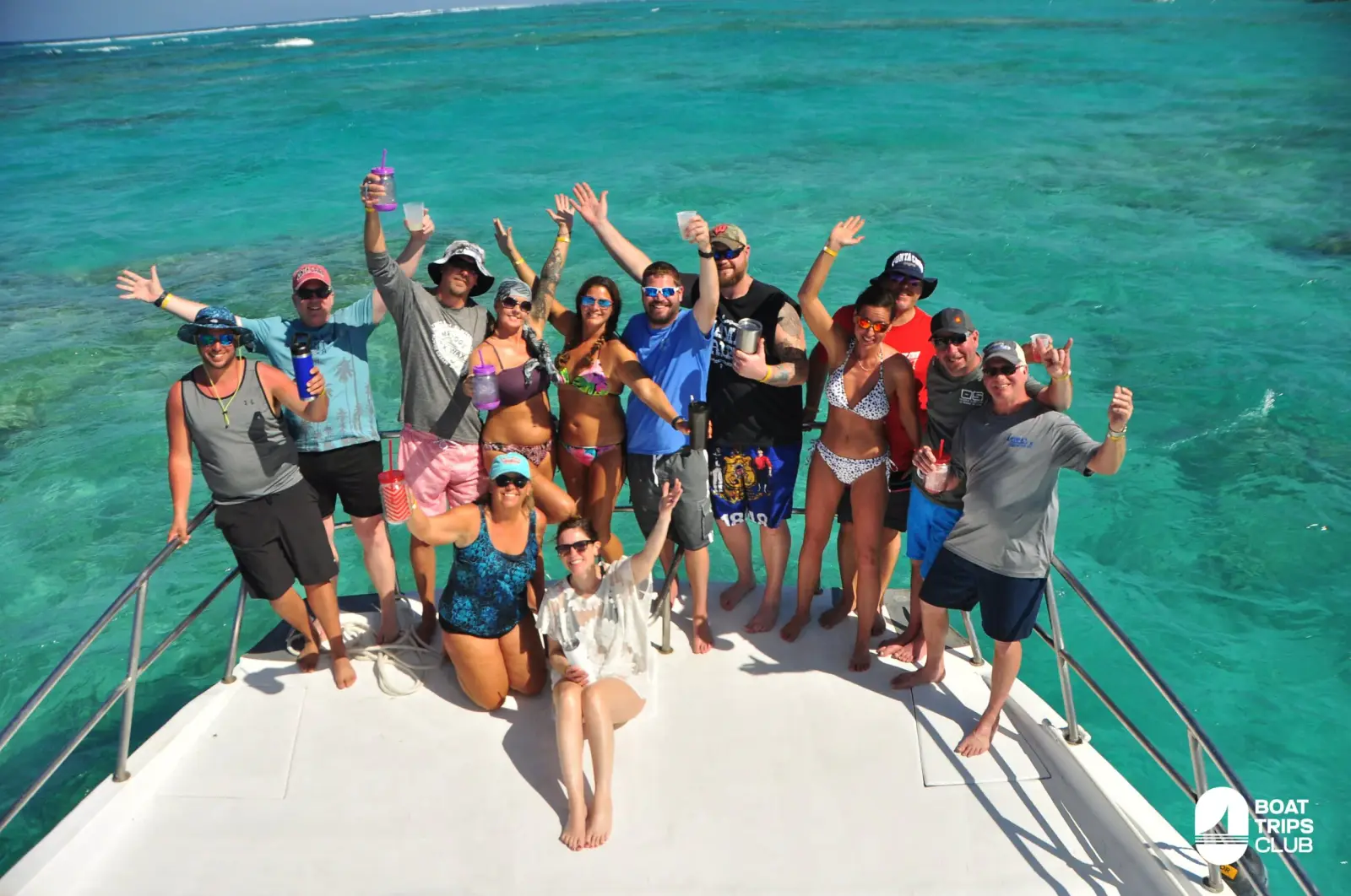 Guests cheer and wave from the bow of the boat over clear turquoise reef water