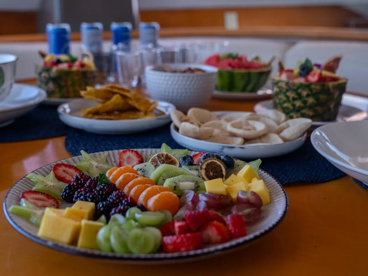 Platter of strawberries, blackberries, kiwi, pineapple and grapes beside bowls of chips and crackers