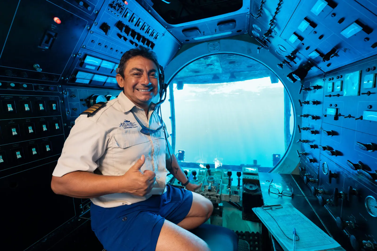 Submarine pilot in uniform giving a thumbs-up at the controls beside the front viewport