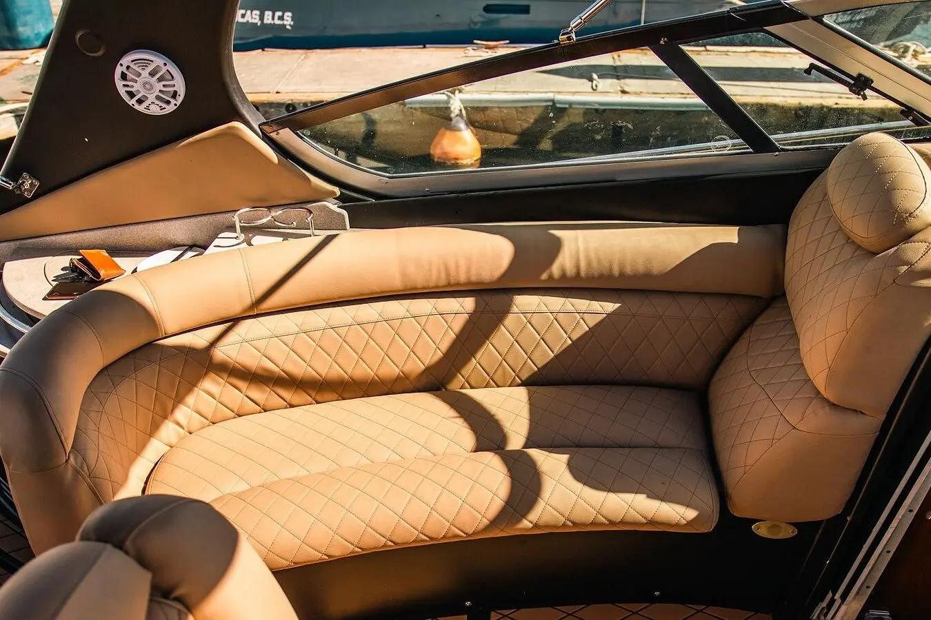 Quilted tan leather lounge seating in a motor yacht's cockpit beneath the curved windshield