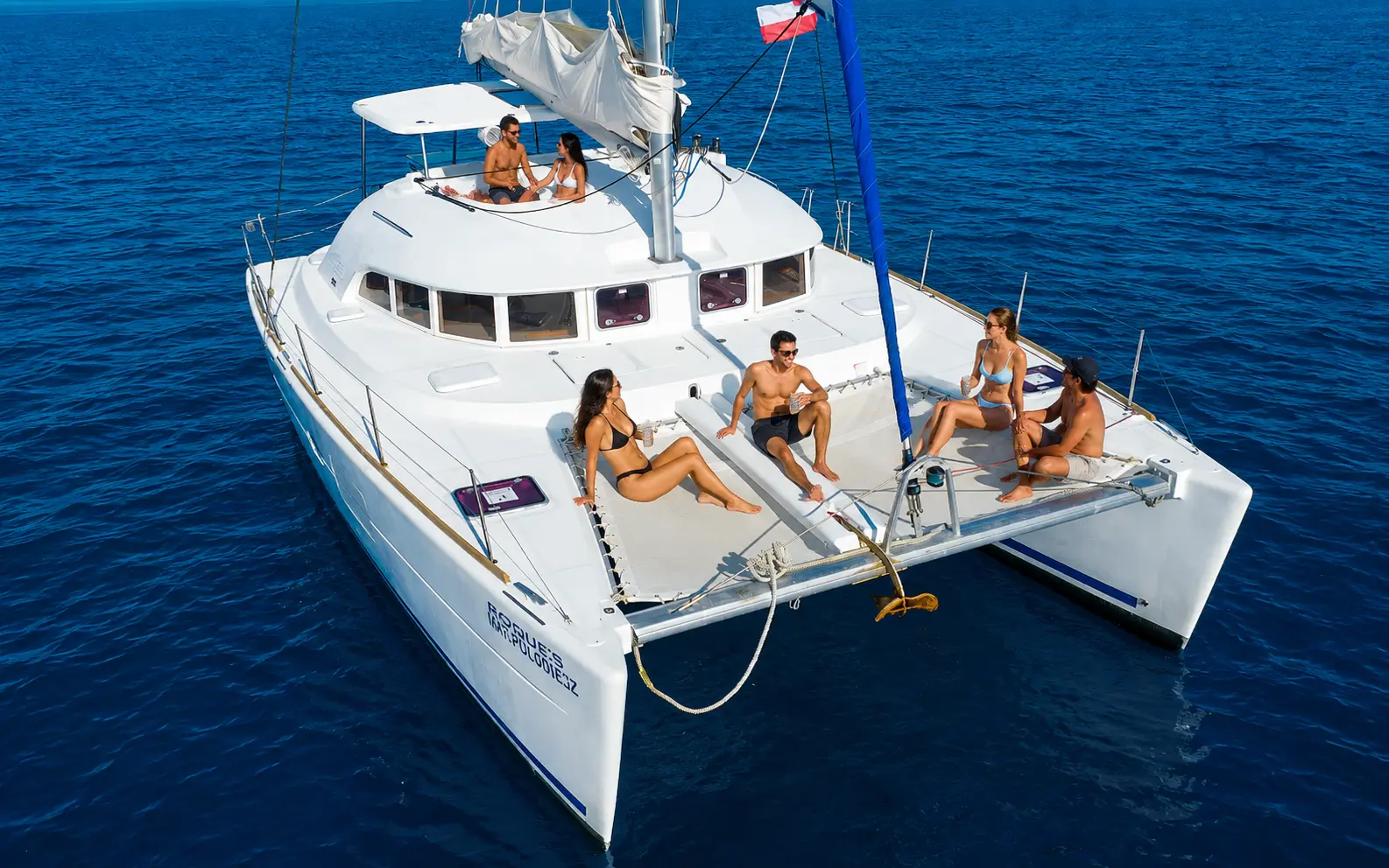 Aerial view of a sailing catamaran with guests lounging on deck off the Riviera Maya