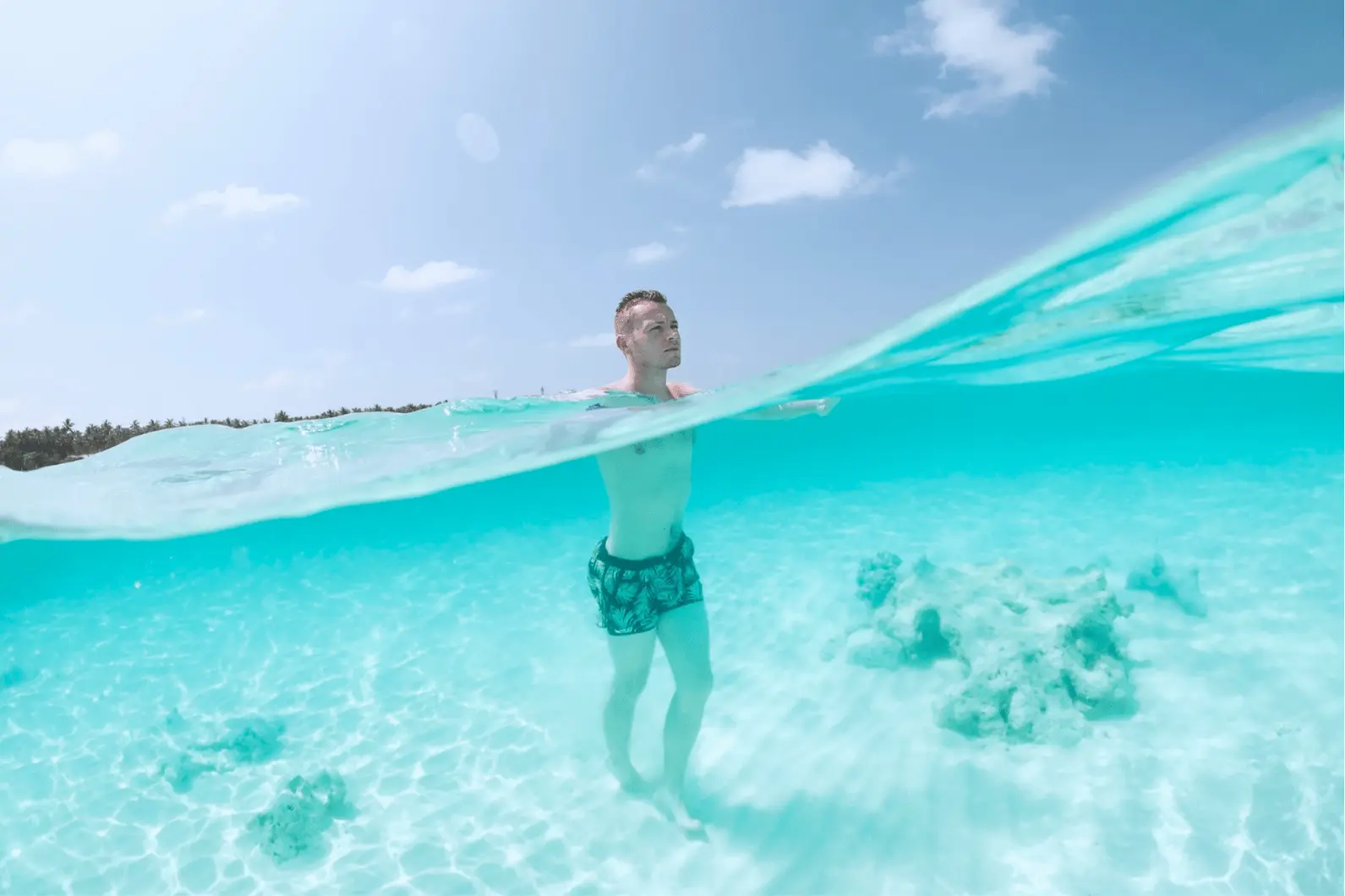 Half-underwater view of a man standing in the clear shallows of Palmilla Natural Pool