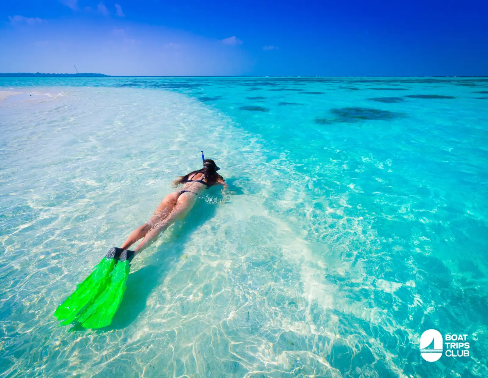 Snorkeler with green fins gliding over a clear sandbar off Saona Island