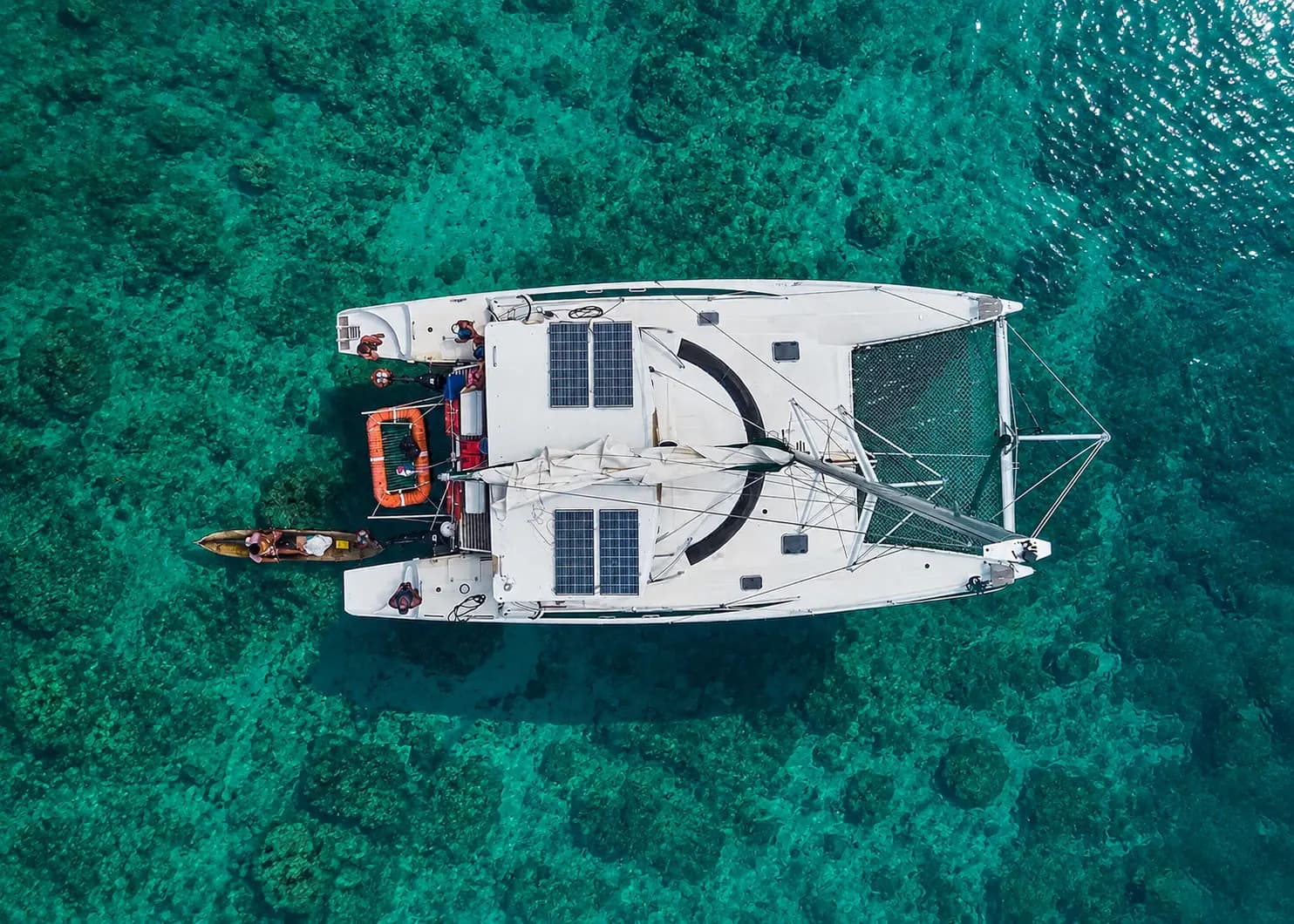Top-down aerial of a sailing catamaran anchored over shallow coral reef in Bocas del Toro