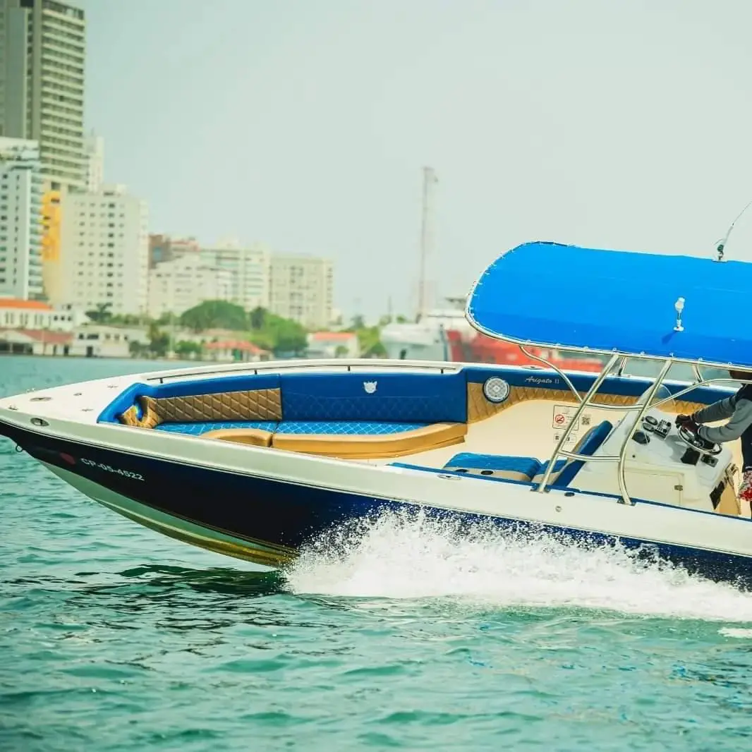 Navy-and-white speedboat with a blue canopy speeding past Cartagena's waterfront high-rises