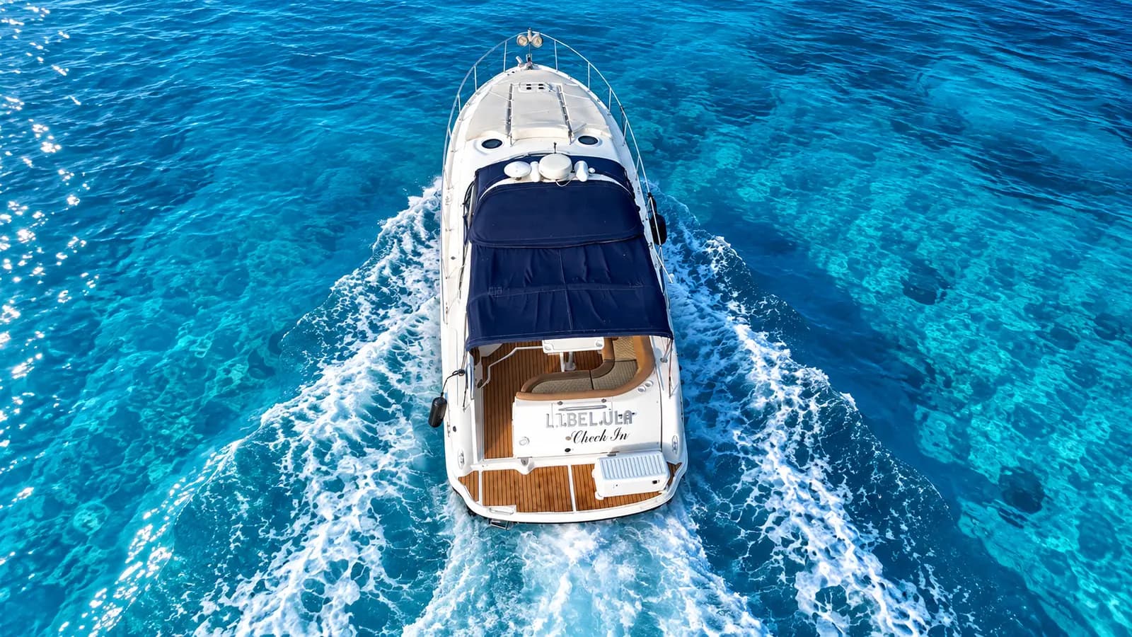 Overhead view of a motor yacht with a navy canopy running through deep blue water off Cancún