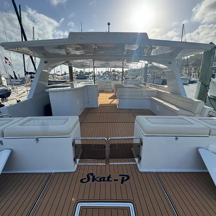 Teak-floored deck with white cushioned seating aboard the power catamaran, moored in a marina