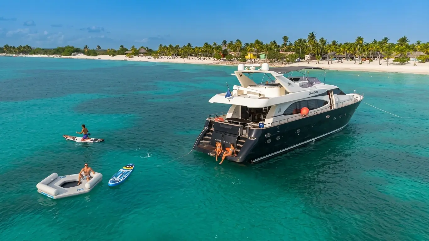 Motor yacht anchored off a palm-lined Punta Cana beach as guests paddleboard and float nearby