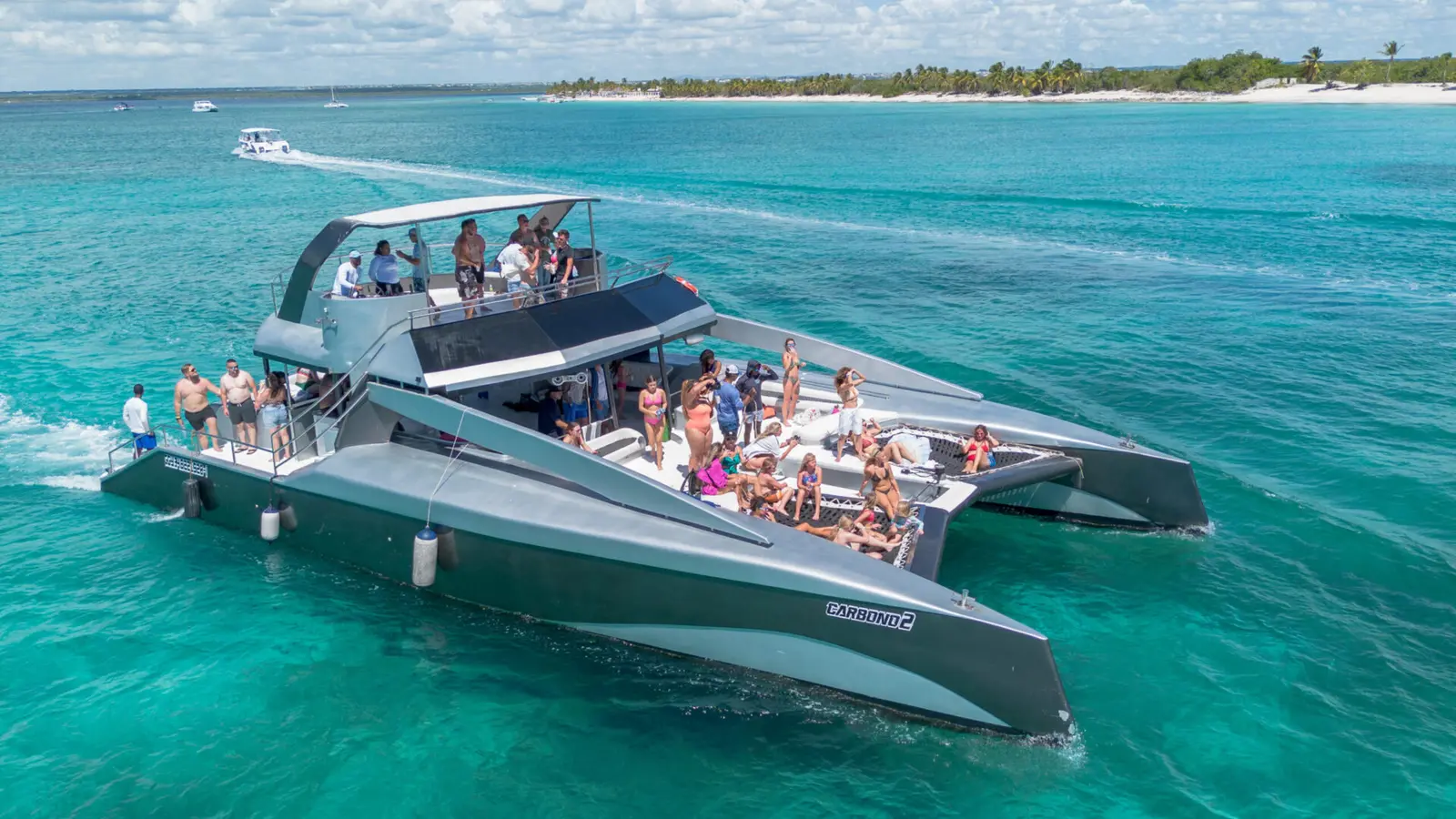 Power catamaran packed with guests cruising turquoise water off the Punta Cana coast