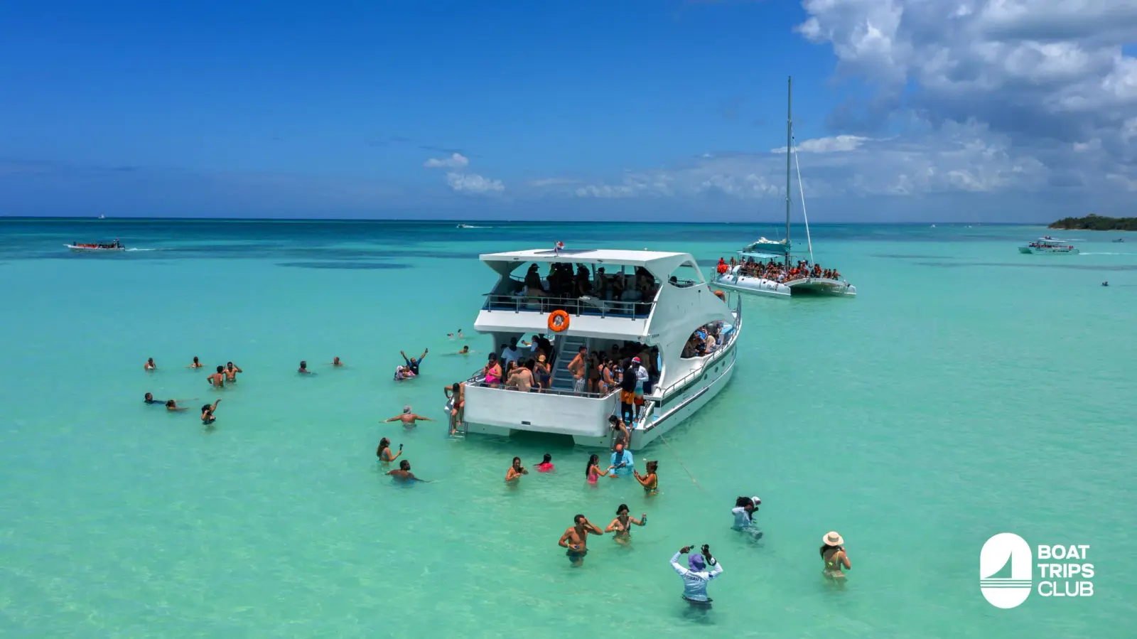 Catamaran anchored in a shallow natural pool near Saona Island as guests wade around it