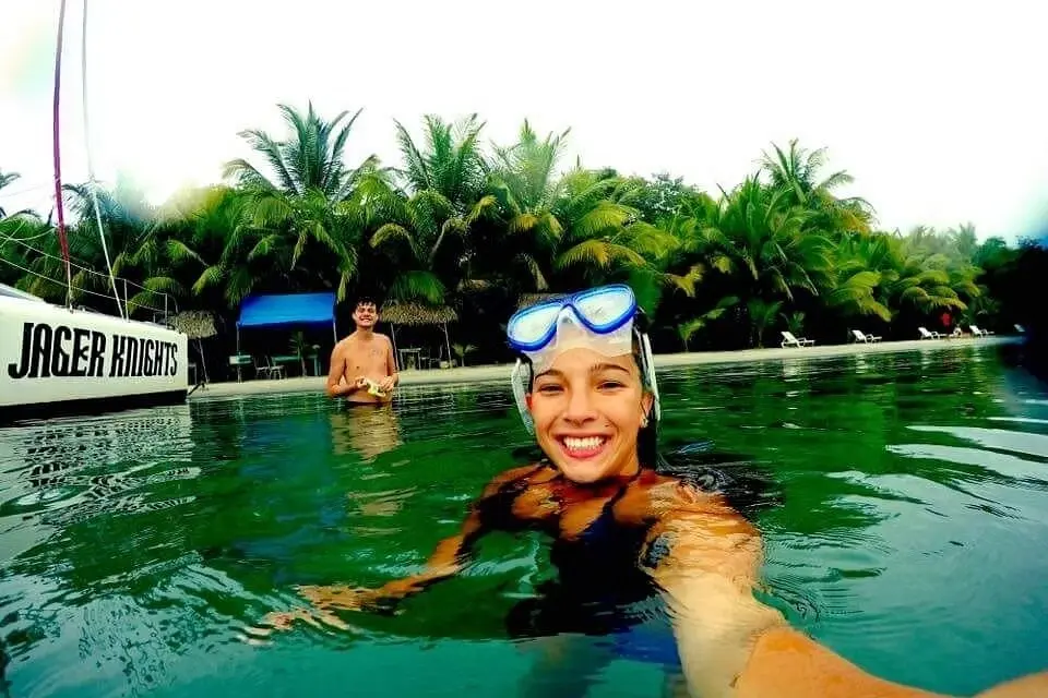 Smiling woman in a snorkel mask taking a selfie beside the catamaran in Bocas del Toro