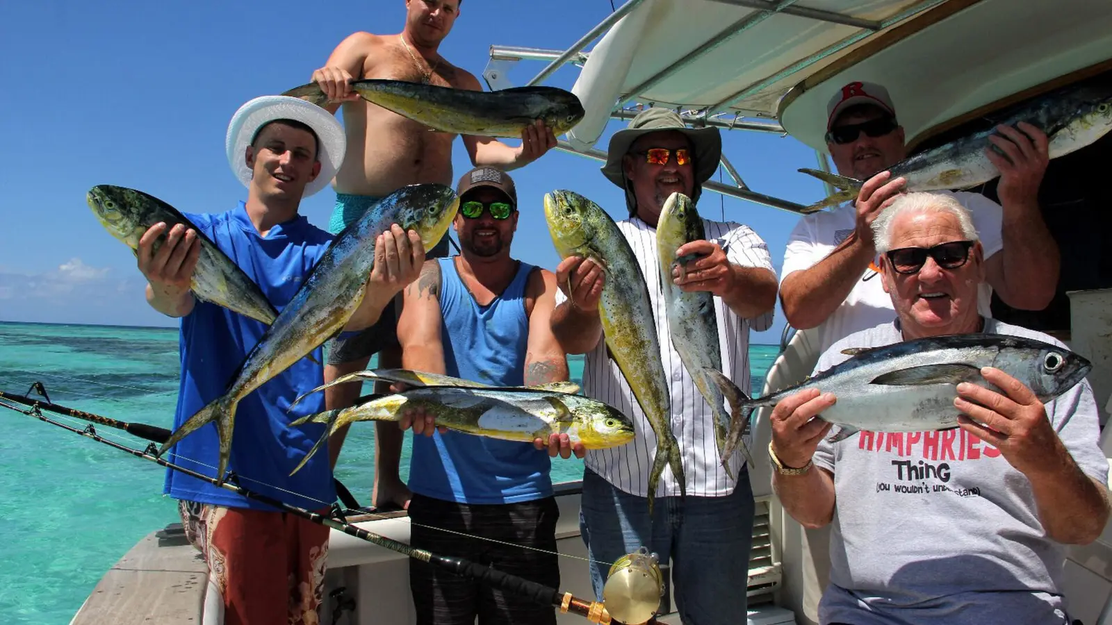 Group of anglers on deck holding up mahi mahi and other fish from the day's catch