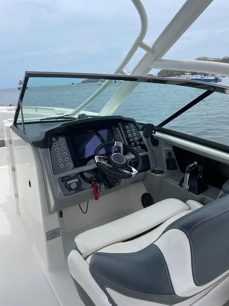 Dual console helm with digital displays, steering wheel and a gray and white bolster seat