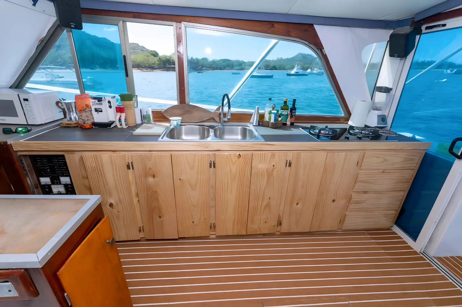 Galley of the sportfishing boat with wood cabinets, a double sink and windows over an anchorage