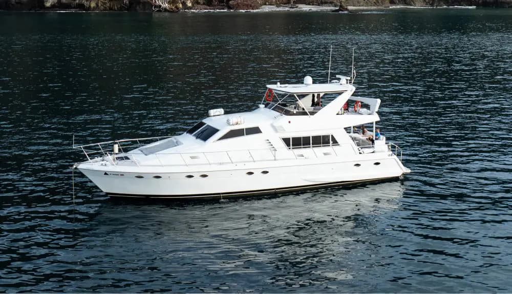 White flybridge motor yacht cruising calm dark water along the Costa Rica coast