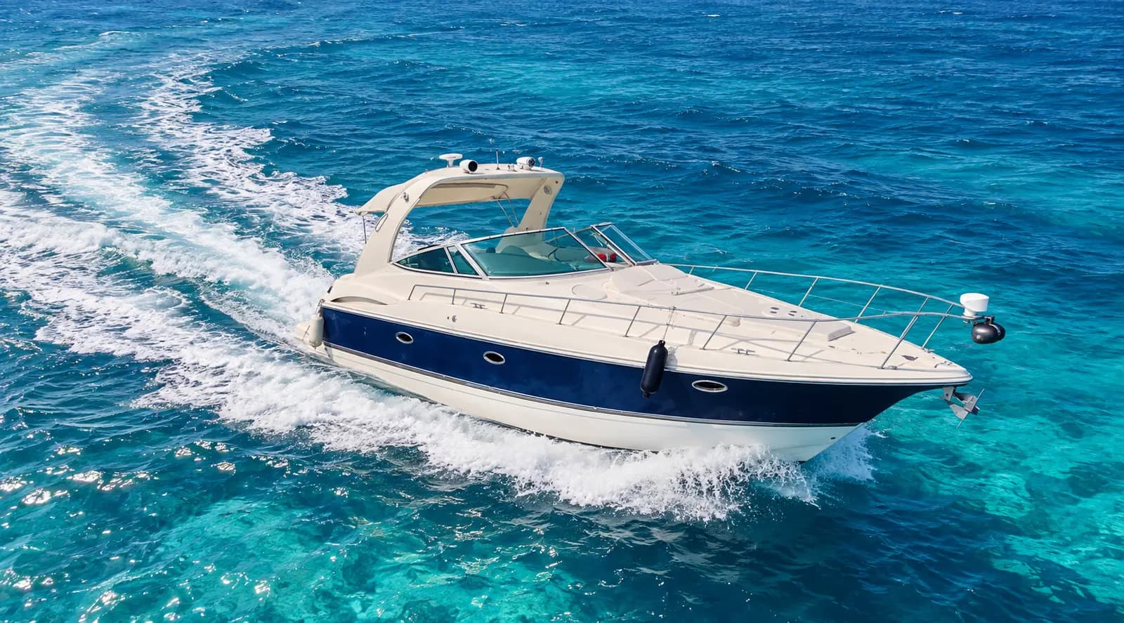Navy-hulled express cruiser cutting a curved white wake across deep blue water near Cancún
