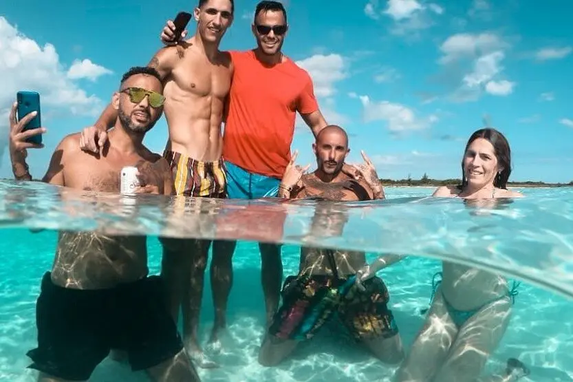 Half-underwater view of five guests standing in clear turquoise shallows at Cayo Arena