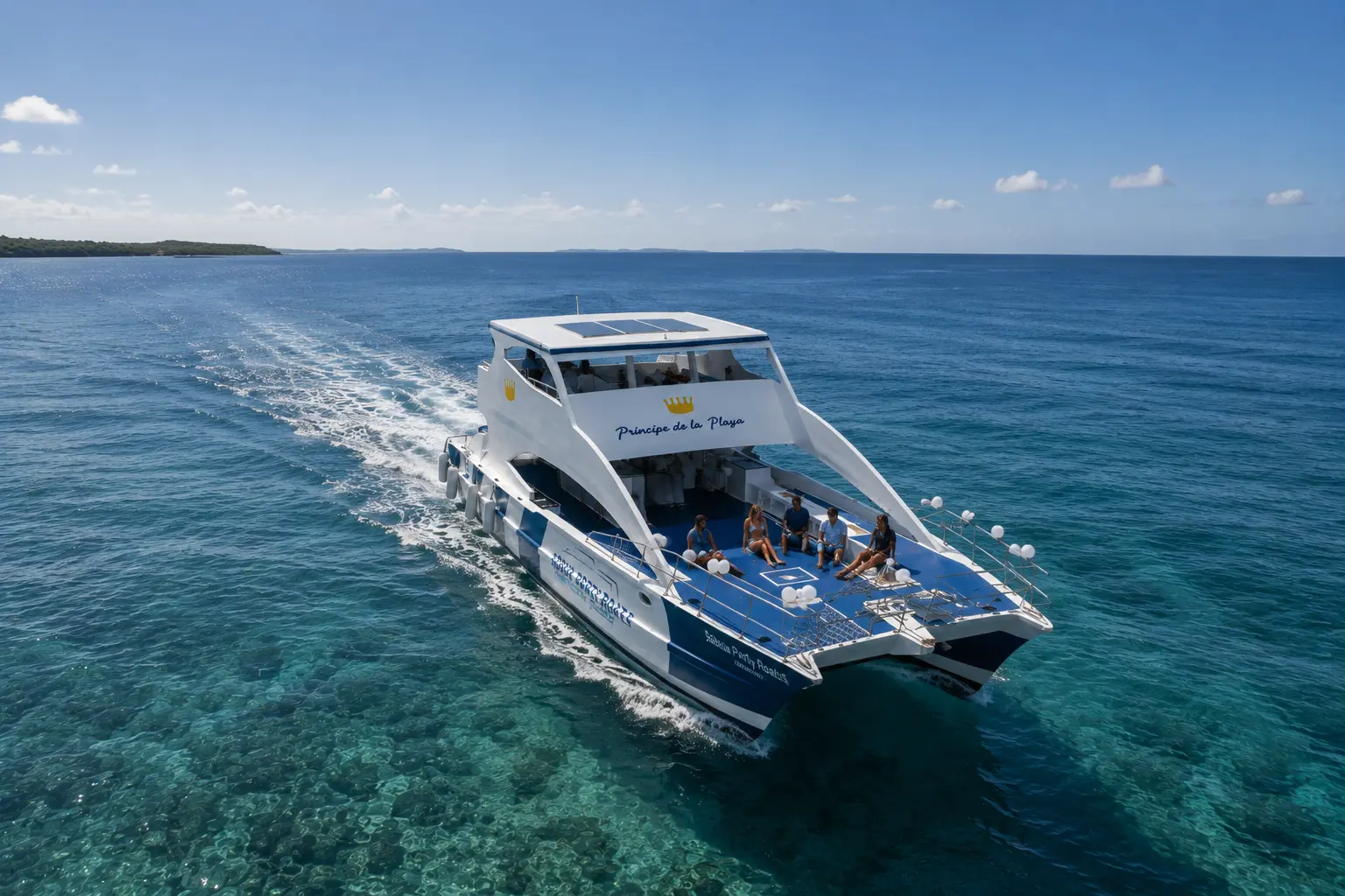 Aerial view of a two-deck power catamaran cruising over clear blue water off Puerto Plata, leaving a wake