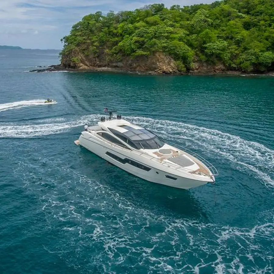 Motor yacht carving a turn past a forested island in Papagayo, a smaller boat nearby