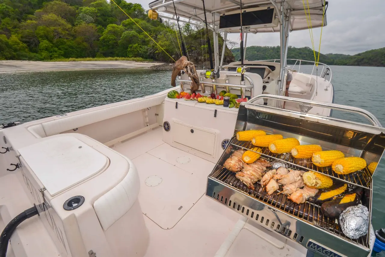 Corn on the cob and meats sizzle on a rail-mounted grill in the fishing boat's cockpit