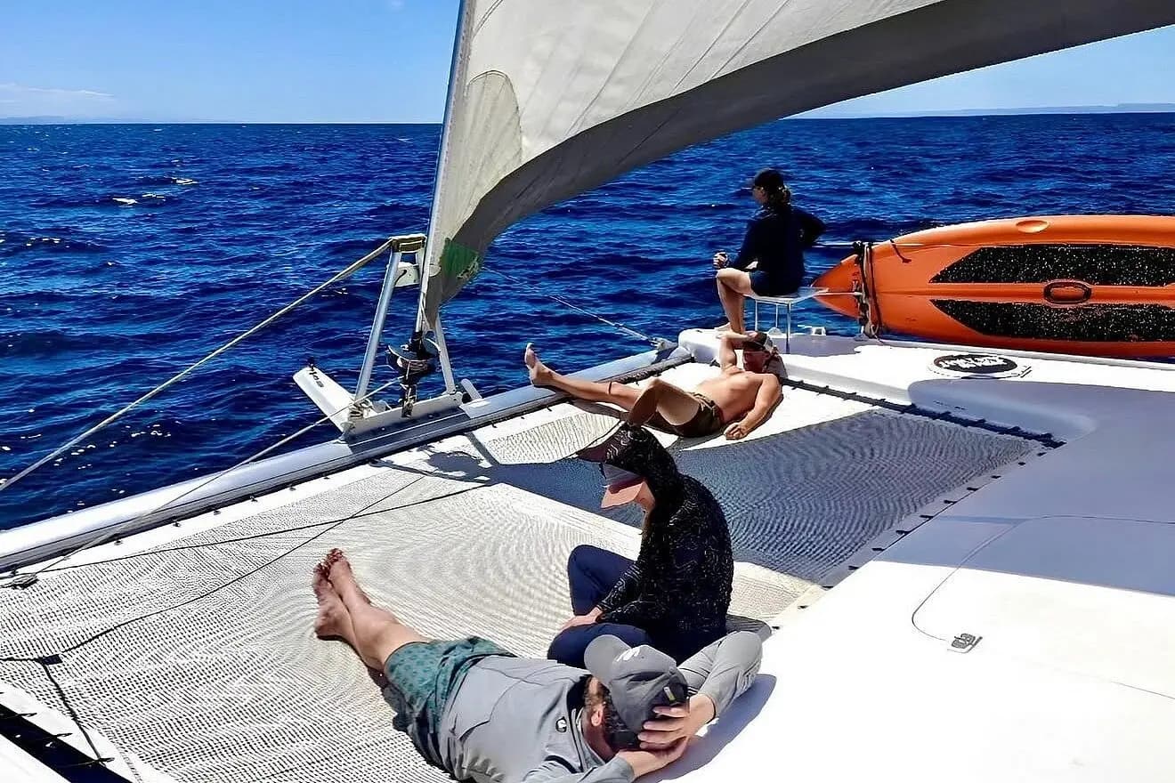 Guests lounging on the trampoline net of a sailing catamaran in the Sea of Cortez