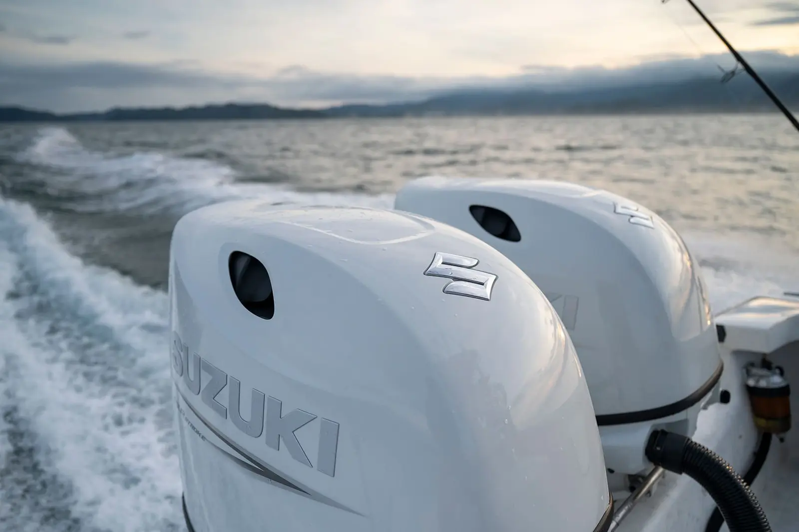 Twin outboard engines churning a white wake behind a center console boat along the Costa Rica coast