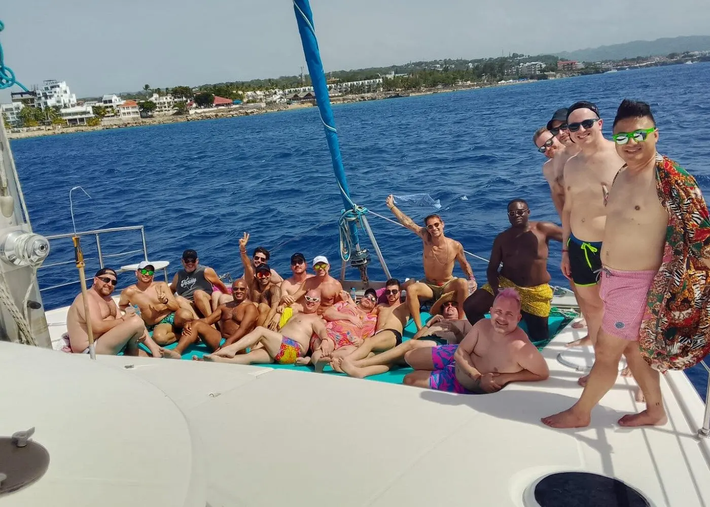 Large group of guests posing and cheering on the bow of a sailing catamaran off the Puerto Plata coast