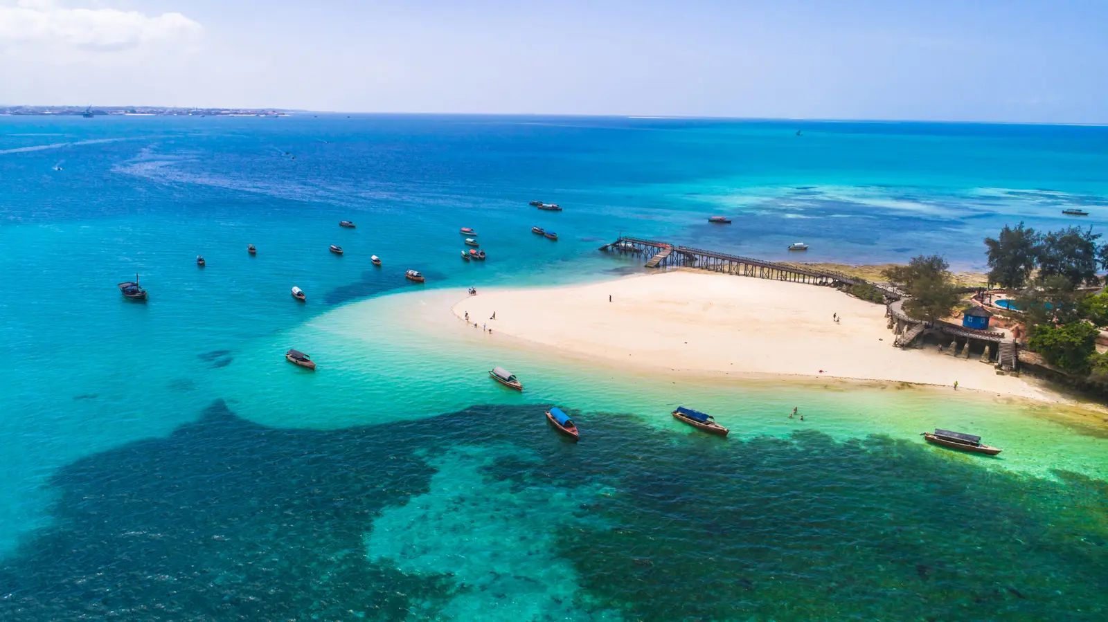 Aerial view of Prison Island's sandy spit and jetty with small boats anchored in turquoise water