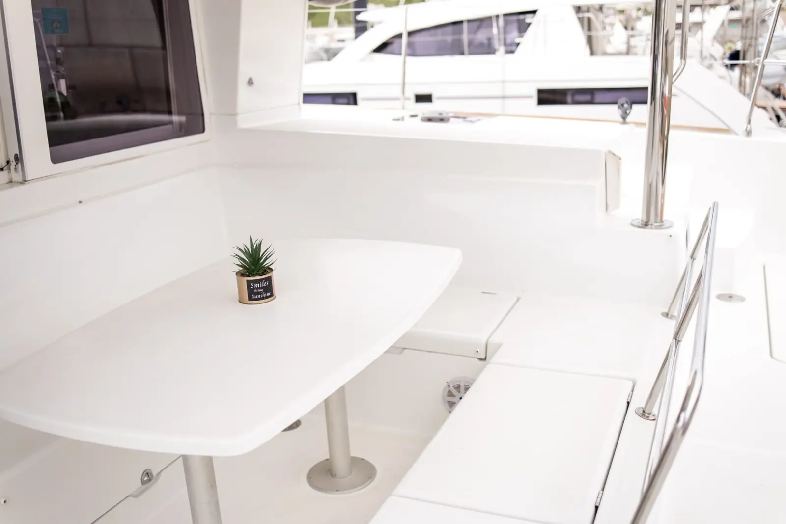 White cockpit table and bench seating on the catamaran's aft deck, a small plant on top