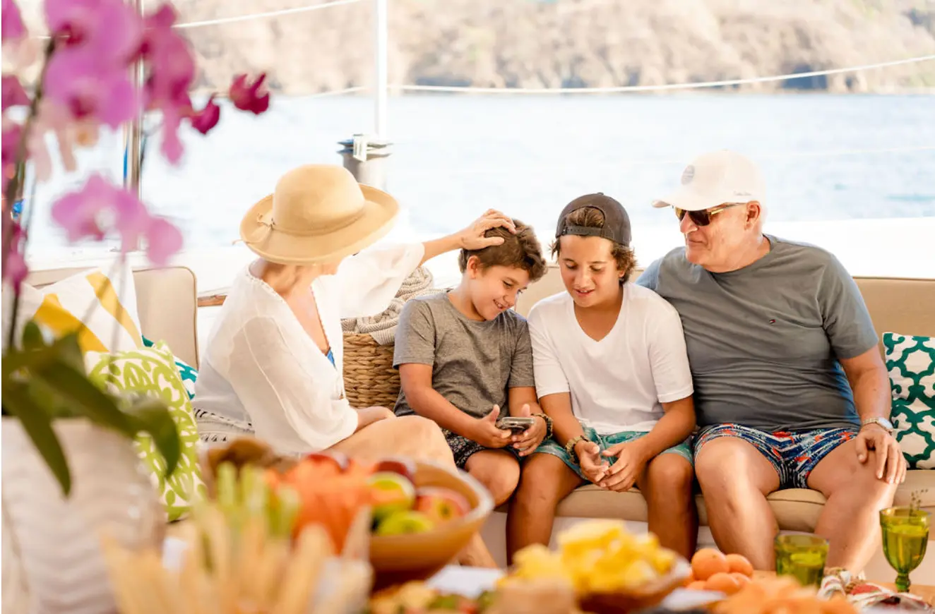 Family with two boys relaxing on the catamaran deck by a fruit platter in the Gulf of Papagayo