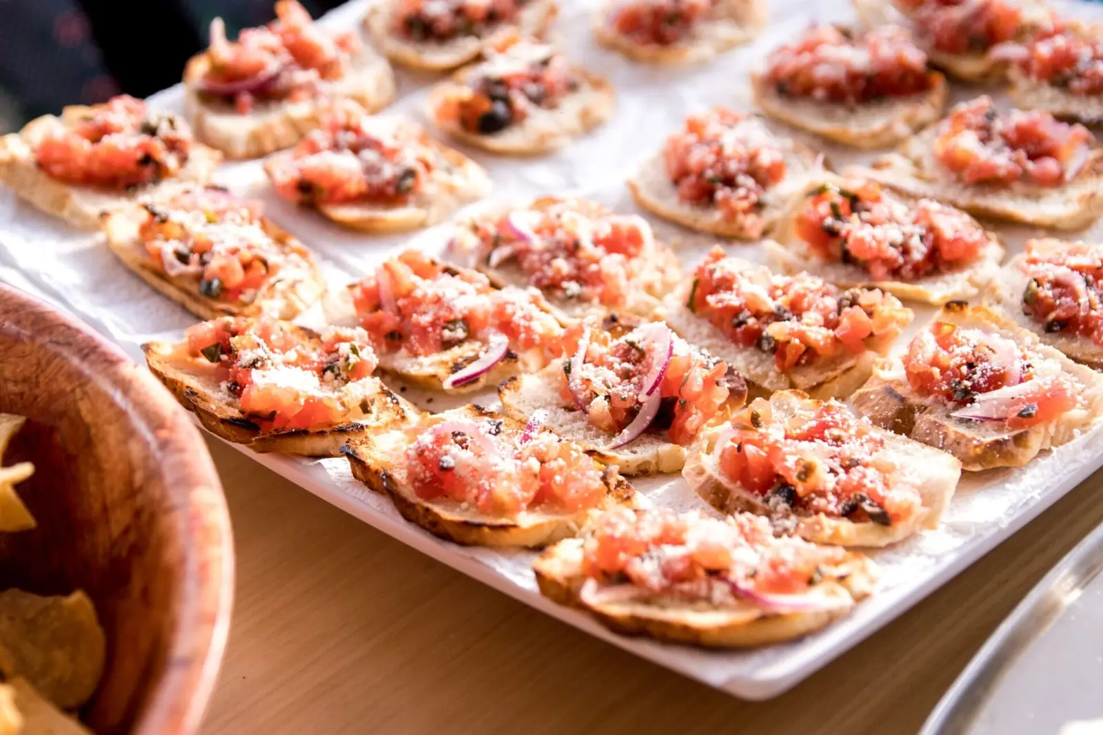 Close-up of a tray of bruschetta topped with diced tomato, red onion and grated cheese
