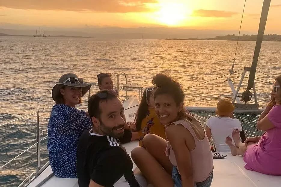 Guests smiling from the bow of a catamaran at sunset over golden water in Bocas del Toro