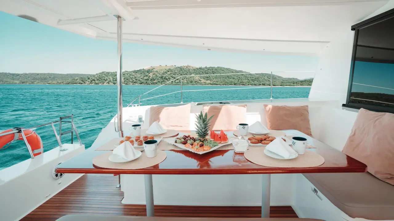 Fruit platter and place settings on the shaded cockpit table of the sailing catamaran