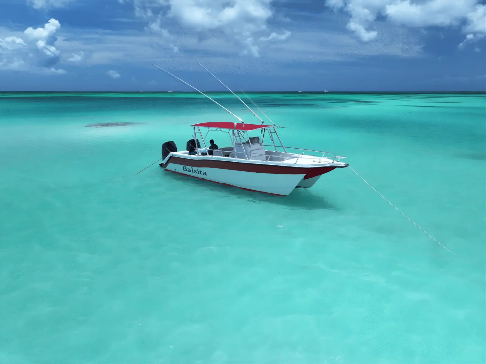 Speedboat with a red T-top anchored alone in wide turquoise shallows off Saona Island