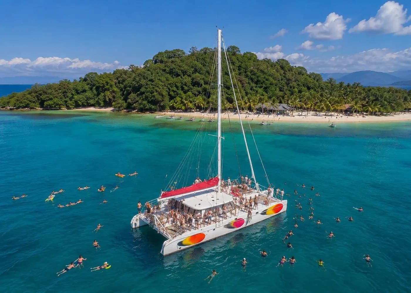 Aerial view of a large sailing catamaran anchored off Cayo Levantado as swimmers fill the water around it
