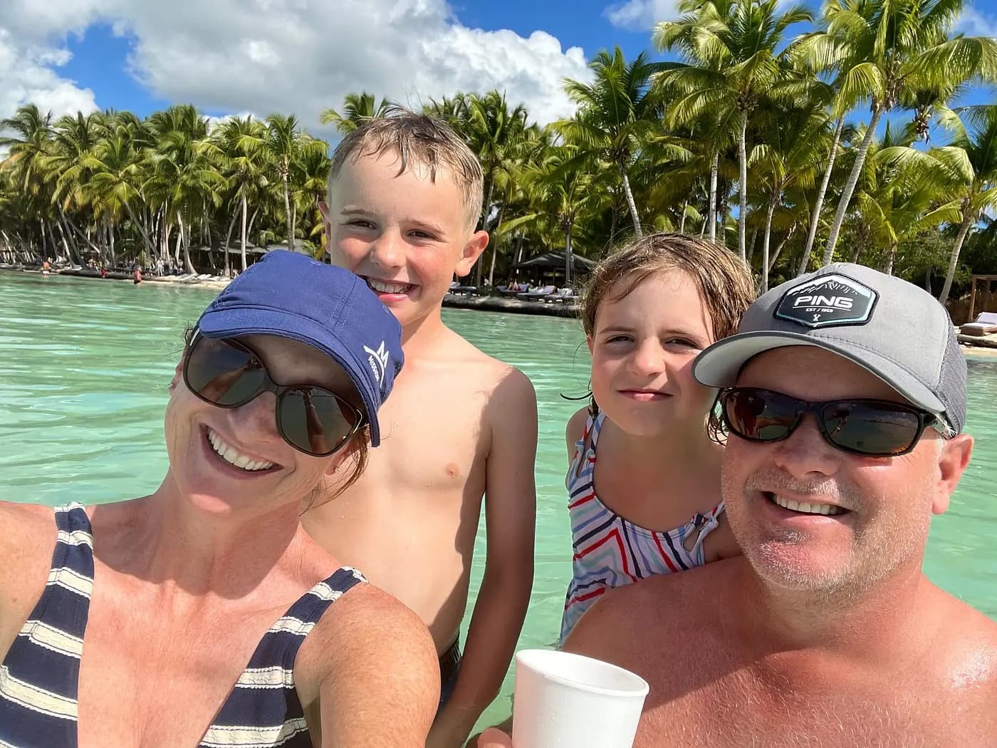 Family selfie in the turquoise shallows of a palm-lined Saona Island beach