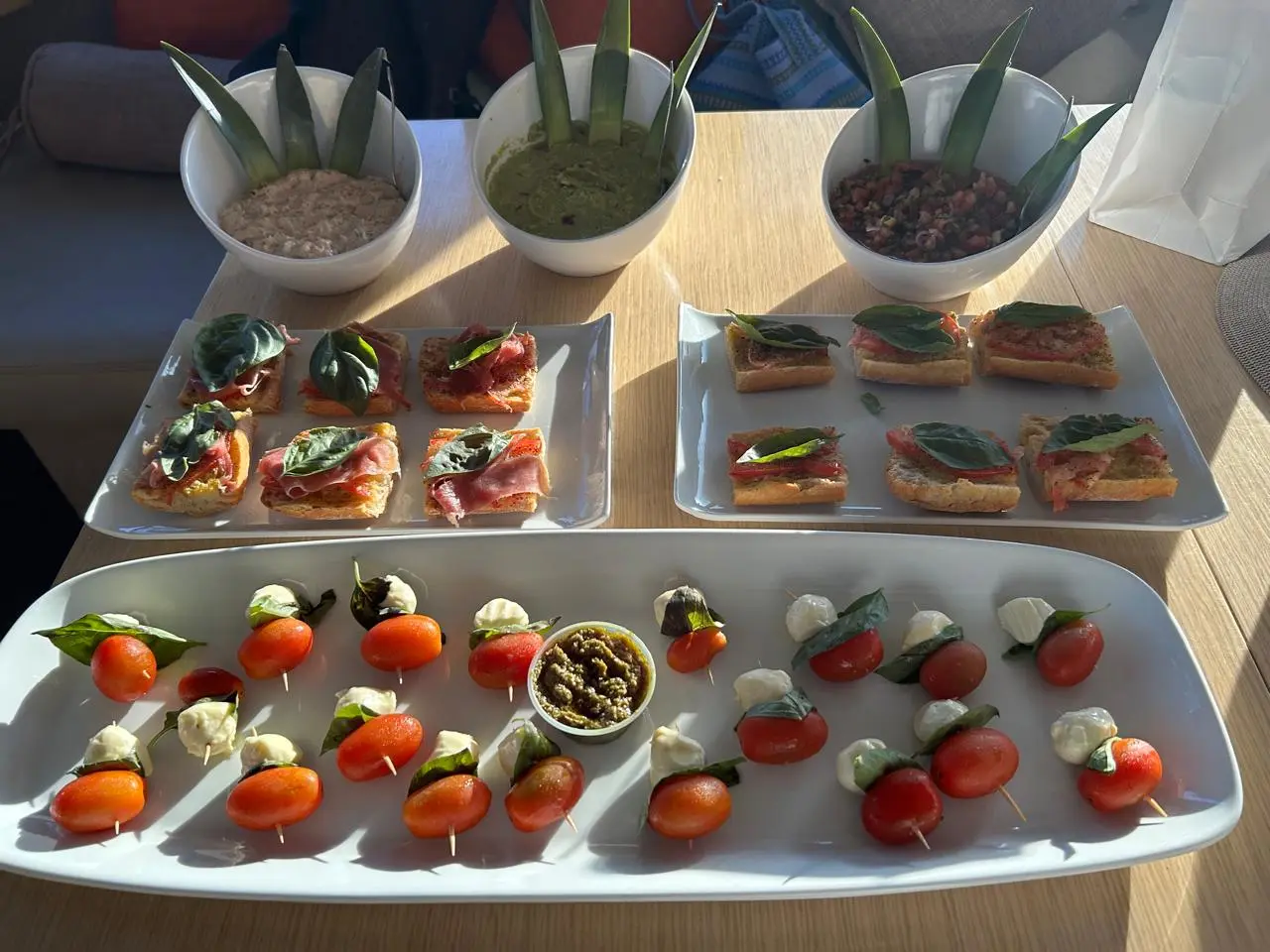 Caprese skewers, prosciutto bruschetta and bowls of dip garnished with pineapple leaves