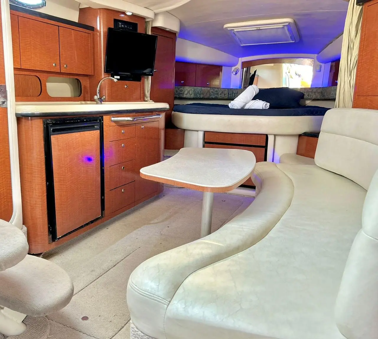 Yacht cabin with a cream leather dinette, galley and the forward berth at the far end
