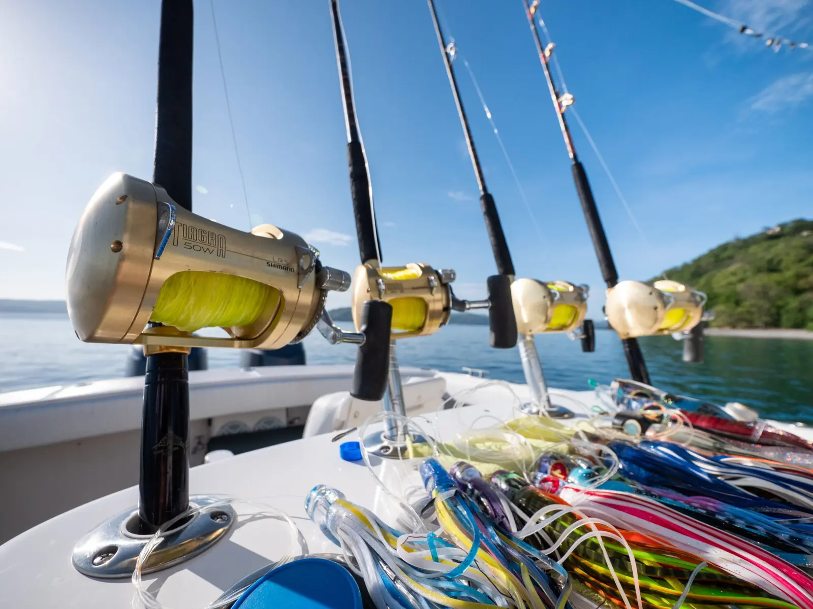 Gold trolling reels and a pile of colorful skirted lures on the deck of the sportfishing boat