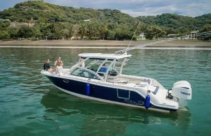 Side view of the center-console boat with outriggers at anchor below jungle-covered hills