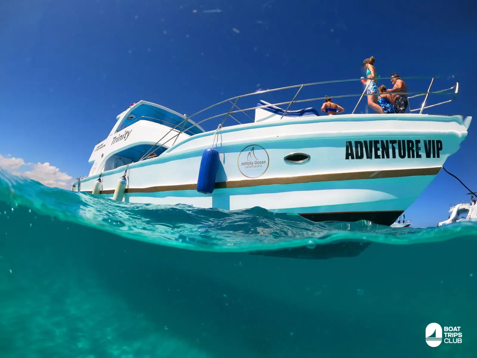 Split-level view of a white catamaran with guests on its top deck above clear turquoise water