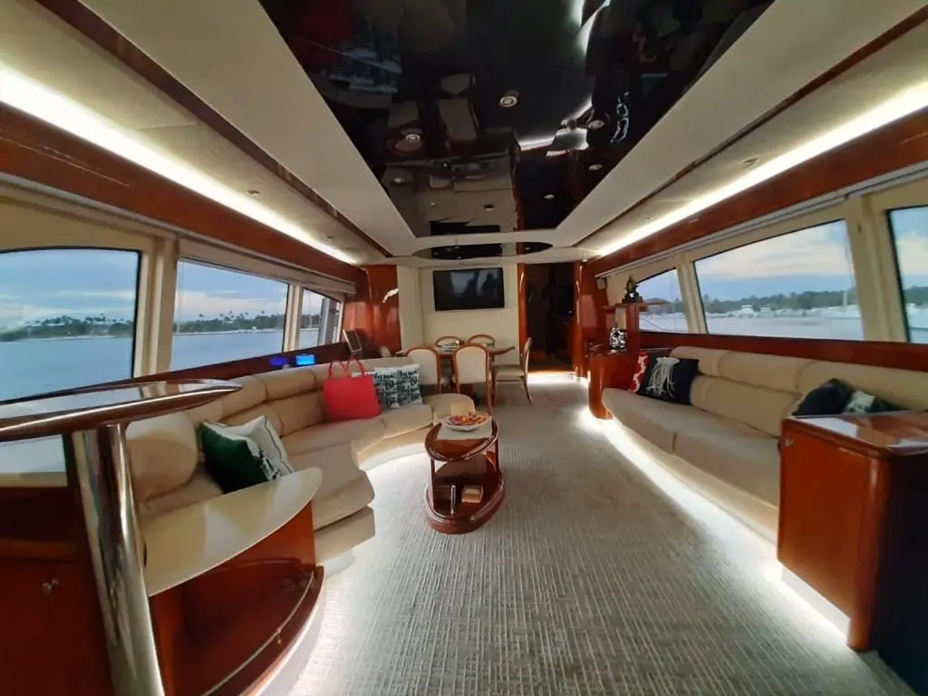 Long yacht salon with cream sofas along both sides, glossy wood trim and wide windows