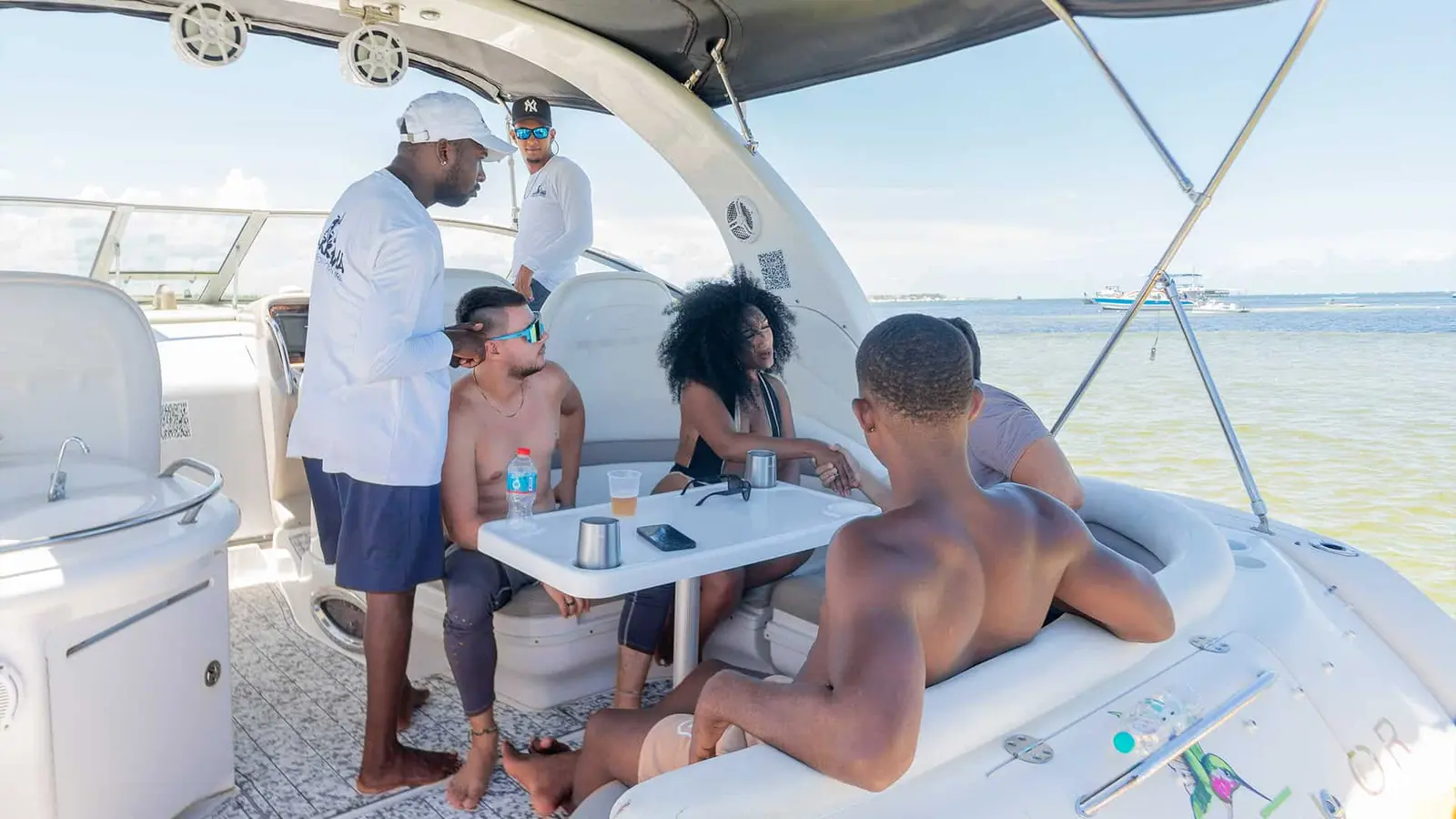 Crew member attending to guests seated at the yacht's shaded cockpit table