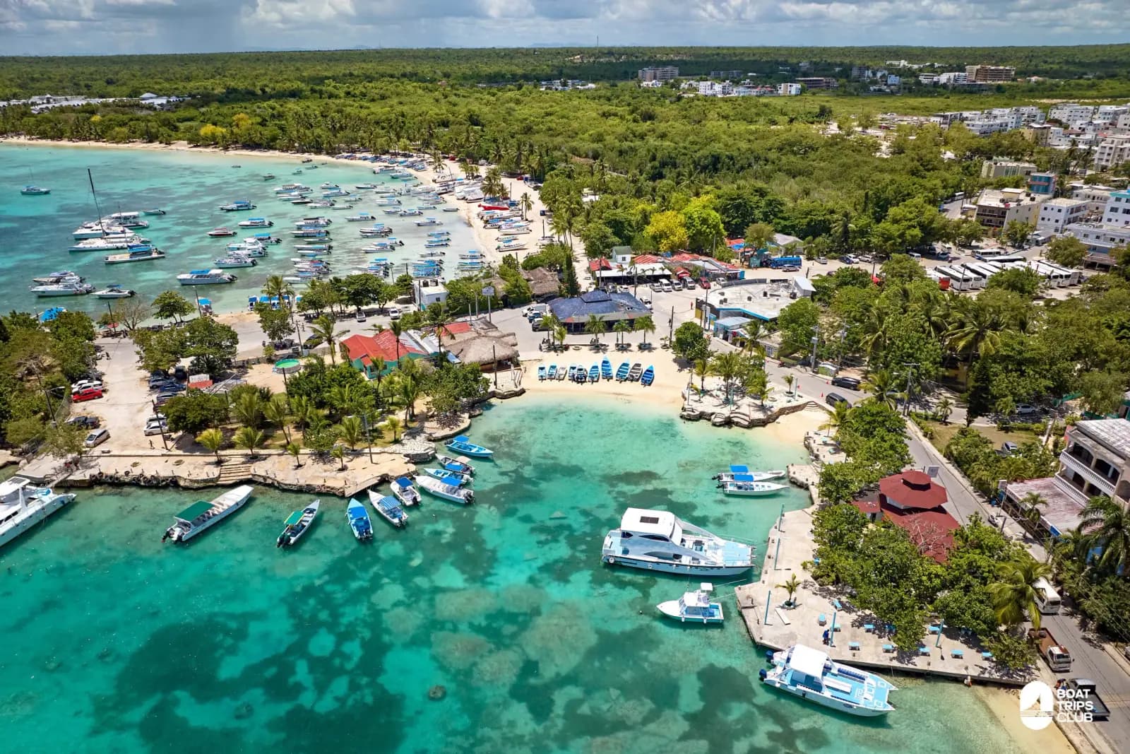 Aerial view of Bayahibe harbor with boats moored in turquoise water beside the village beach