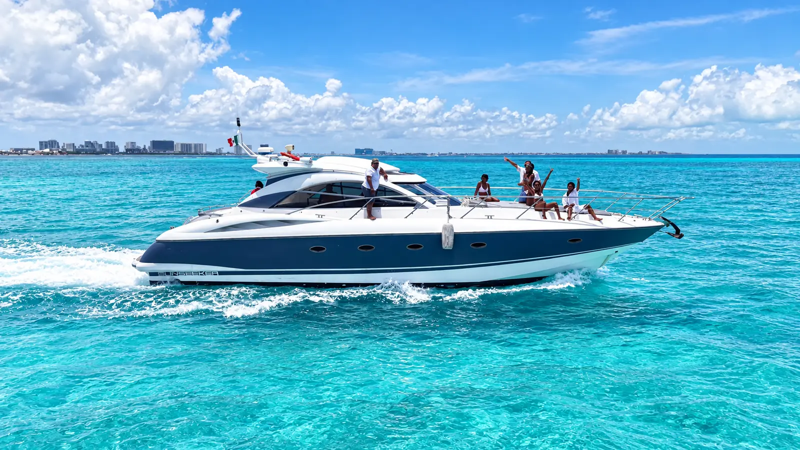 Navy-hulled sport yacht speeding over turquoise water, guests waving from the bow, Cancún skyline behind