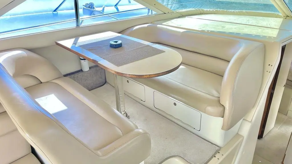 Cream leather dinette around a wooden table in the bright saloon of a motor yacht