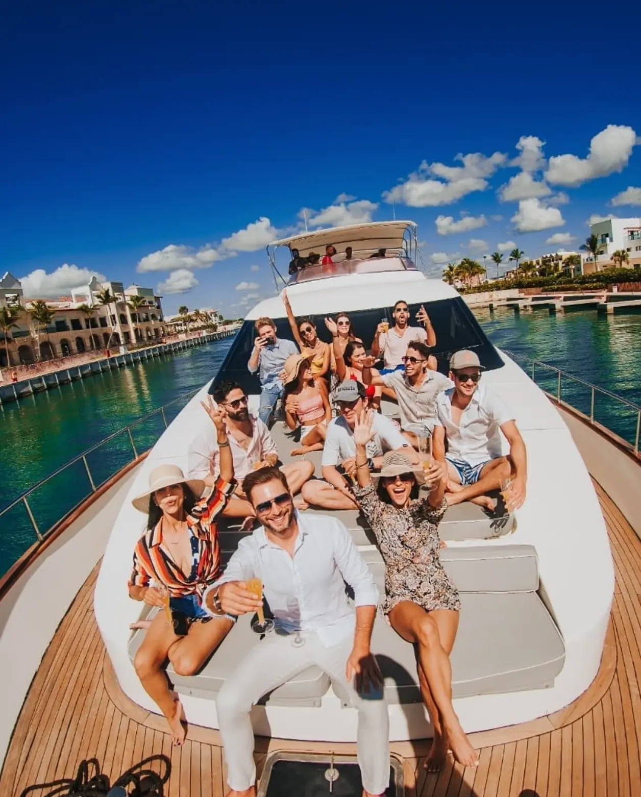 Large group of guests posing together on the yacht's bow in a marina