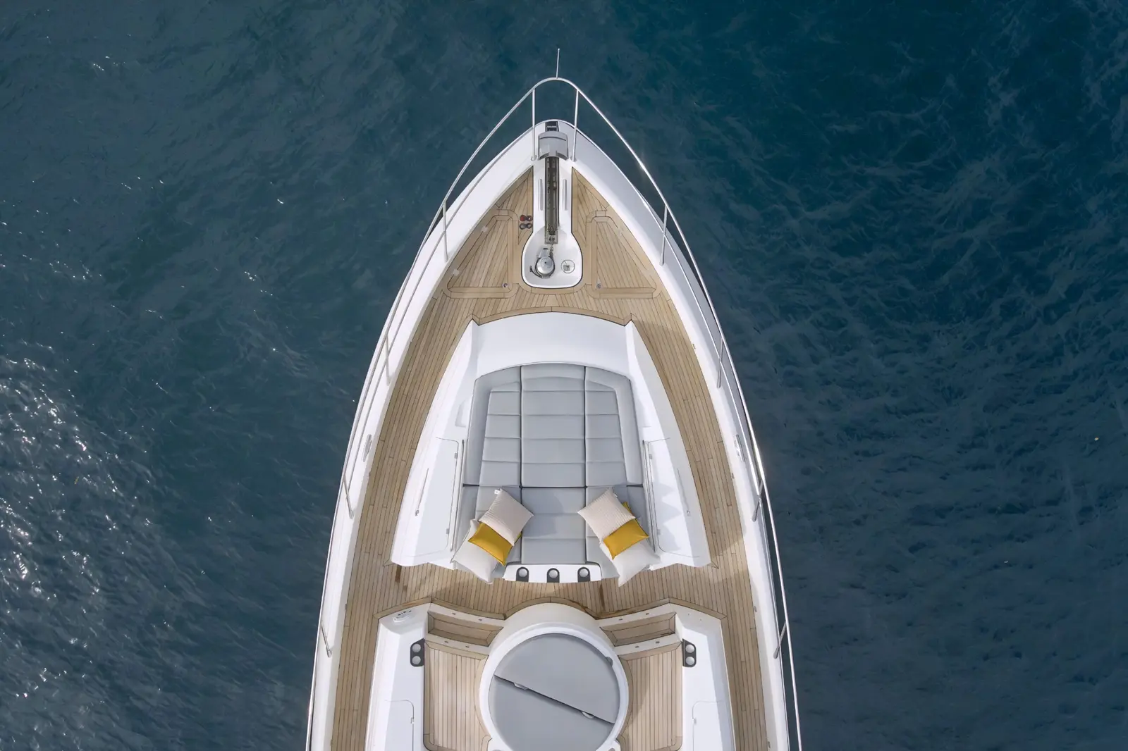 Top-down aerial view of the motor yacht's teak foredeck and bow sunpad over deep blue Papagayo water